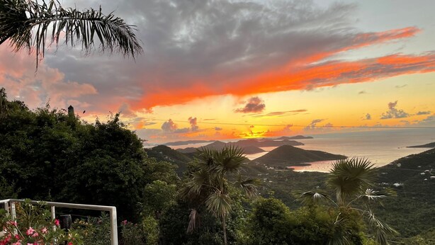 A pool area with a view of the sunset over a coastal landscape. - MandeVilla Cottage at Ixora spectacular views AC in bedroom mid island location. (St.John)