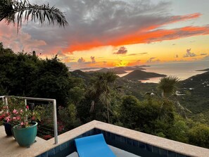 Un espace piscine offrant une vue sur le coucher de soleil au-dessus d’un paysage côtier.