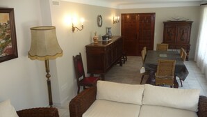 A dining area with a table, chairs, and a cabinet. - Spacious apartment in villa with large private garden and terrace near the sea (Anglet)