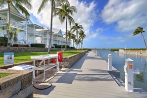 A waterfront hotel with a dock, palm trees, and a clear sky.