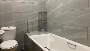 A bathroom with a toilet, a glass shower enclosure, and a bathtub. - Three Bed Two Bath Apartment in London (London)