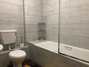 A modern bathroom with a toilet, sink, and a walk-in shower with a glass enclosure. - Three Bed Two Bath Apartment in London (London)