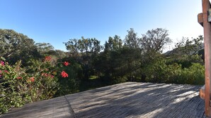 A wooden deck with a view of a forested area and a clear blue sky.