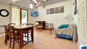A dining area with a wooden table and chairs, a TV mounted on the wall, and a Buddha painting.