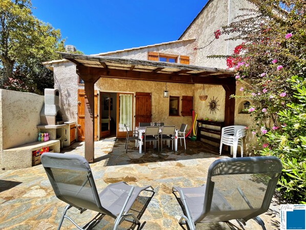 A patio area with stone flooring, outdoor furniture, and a pergola structure.