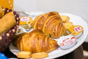 Un plato con croissants y un tarro de yogur con miel.