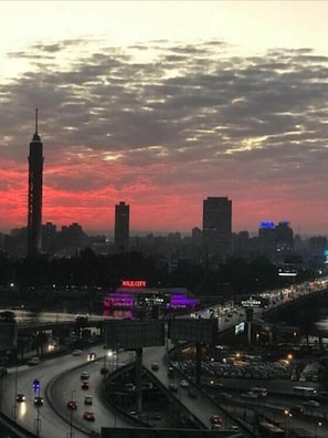 A cityscape at dusk with a prominent tower and a bridge with traffic.