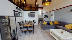 A spacious living area with a wooden dining table, black chairs, a grey sofa with yellow cushions, and a white coffee table. - Hu1 Boutique City Apartment - Sleeps 6 (Hull)