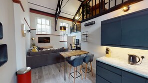 Un espacio habitable compacto con sofá, mesa de comedor y zona de cocina.