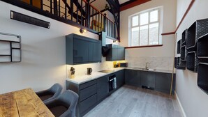 A modern kitchen with dark cabinetry, a marble countertop, and a window providing natural light.