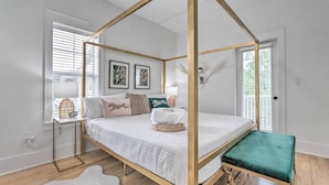 Una cama con dosel de madera, una mesita de noche con lámpara y un banco.
