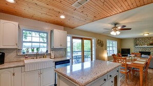 A spacious kitchen with white cabinets, a granite countertop, and a dining area with wooden furniture. - Sunny Lakefront Family Paradise w/ Deck & 2 Kayaks (Granbury)