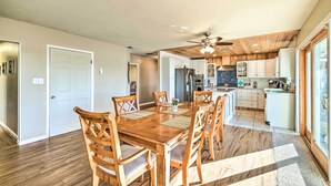 A spacious dining area with a wooden table and chairs, a ceiling fan, and a view of the kitchen and living area. - Sunny Lakefront Family Paradise w/ Deck & 2 Kayaks (Granbury)