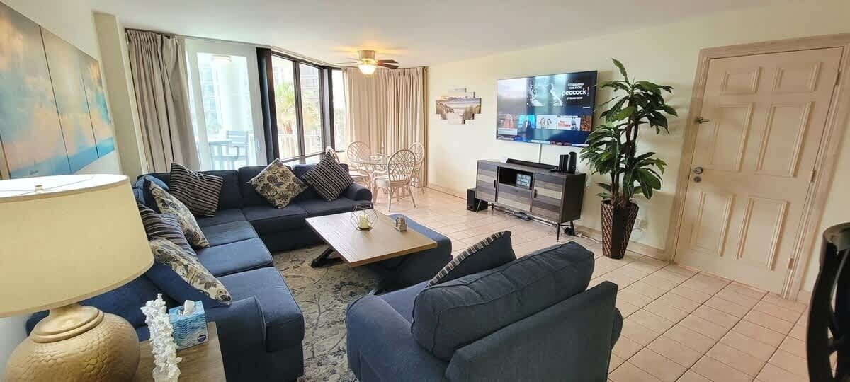 Een woonkamer met een bank, een salontafel, een televisie en een plant.