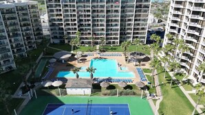 Ein Hochhaus-Hotel mit mehreren Balkonen, einem zentral gelegenen Schwimmbad und Außenbereichen mit Sitzgelegenheiten.