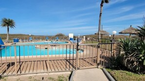 Ein Poolbereich mit mehreren Schwimmbecken, Liegestühlen und Palmen.