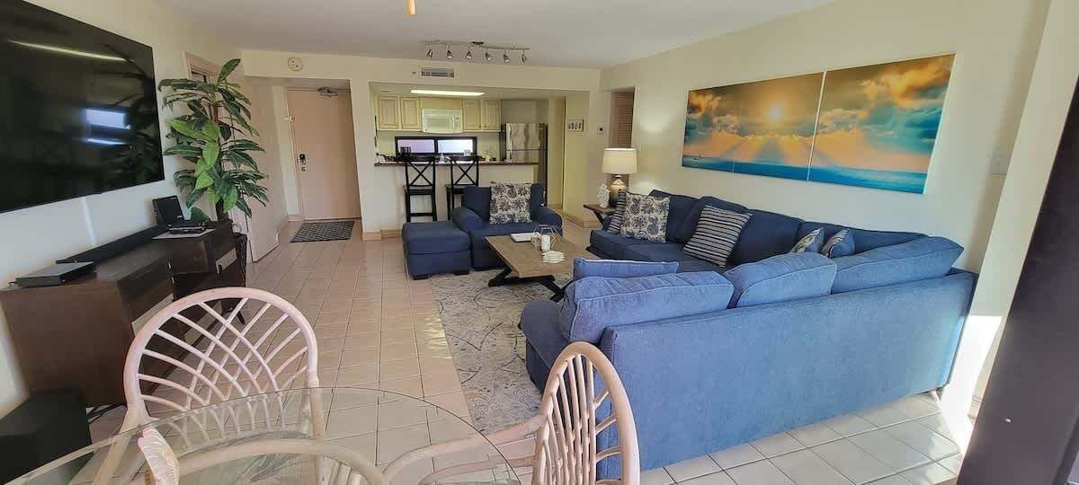 A living room with a blue sofa, a TV, and a dining area with a table and chairs.