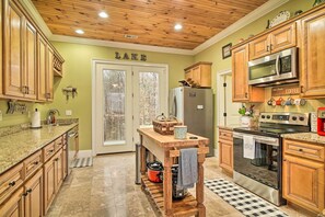 A kitchen with wooden cabinets, a granite countertop, a stove, a microwave, and a refrigerator. - Dog-Friendly Family Home Steps to Norris Lake (Sharps Chapel)