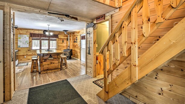 A wooden cabin interior with a wooden staircase, a kitchen area, and a dining space. - Pet-Friendly Brantingham Cabin by ATV Trails (Brantingham)