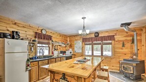 A wooden cabin kitchen with a central island, a stove, and a refrigerator. - Pet-Friendly Brantingham Cabin by ATV Trails (Brantingham)