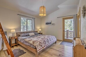 Relax in this serene bedroom with a large bed, bedside tables, and a window offering a view of the surrounding trees.