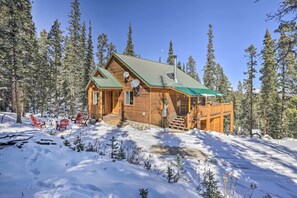 Surrounded by a snowy forest, this cabin features a deck with comfortable seating for outdoor relaxation.