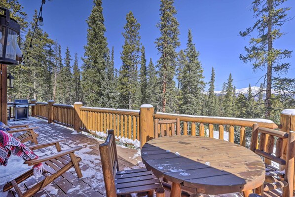 Guests can enjoy al fresco dining on the deck, surrounded by evergreen trees.