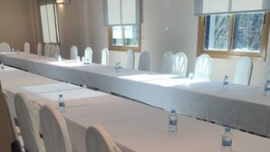 Un salón de conferencias con largas mesas y sillas, cada una con una botella de agua encima.