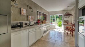 A kitchen with white cabinets, a sink, and a dining area with red chairs.