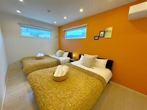 A hotel room with two beds, a window, and an air conditioning unit.