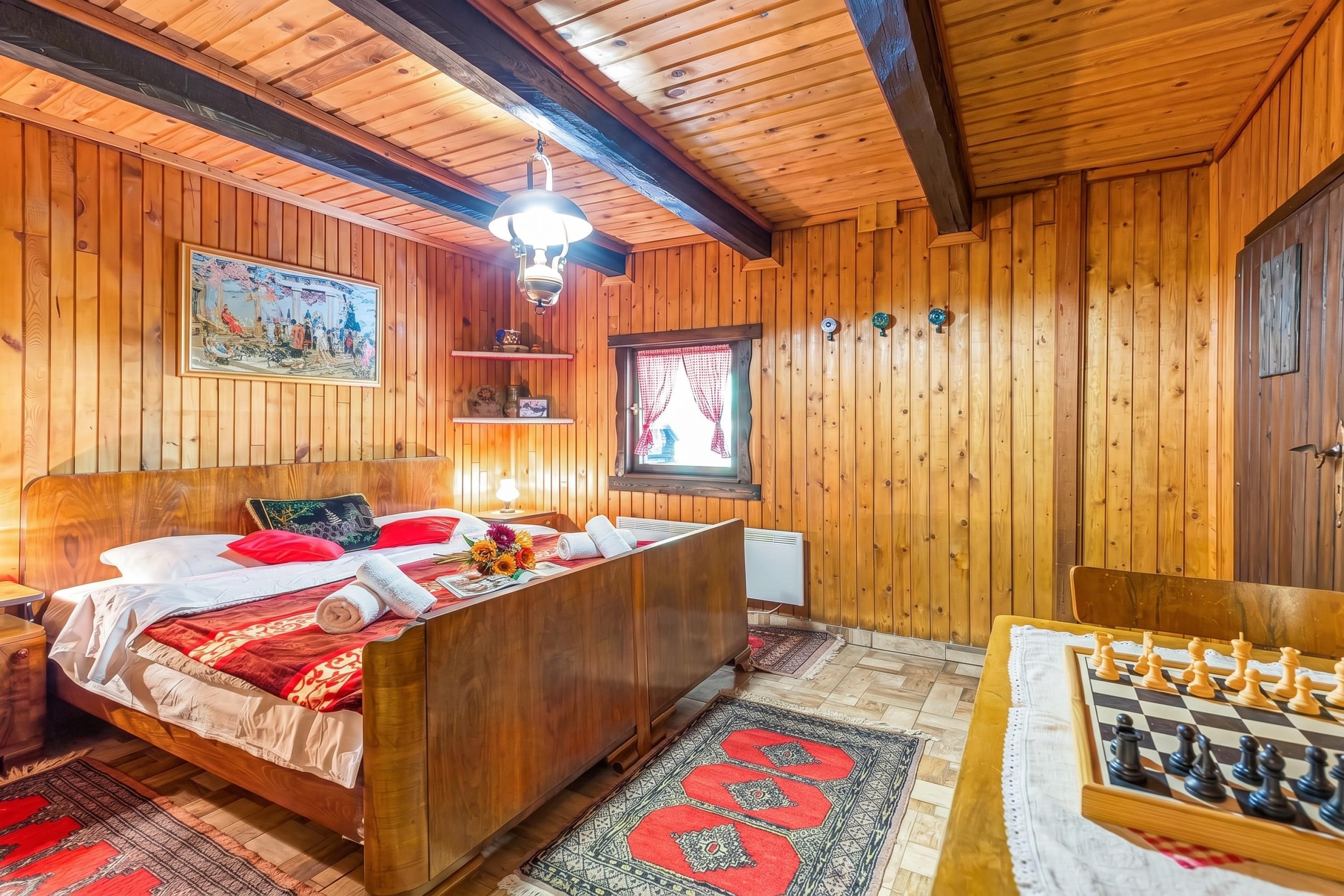 A wooden room with a bed, a desk, and a chessboard.