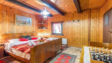 A wooden room with a bed, a desk, and a chessboard.