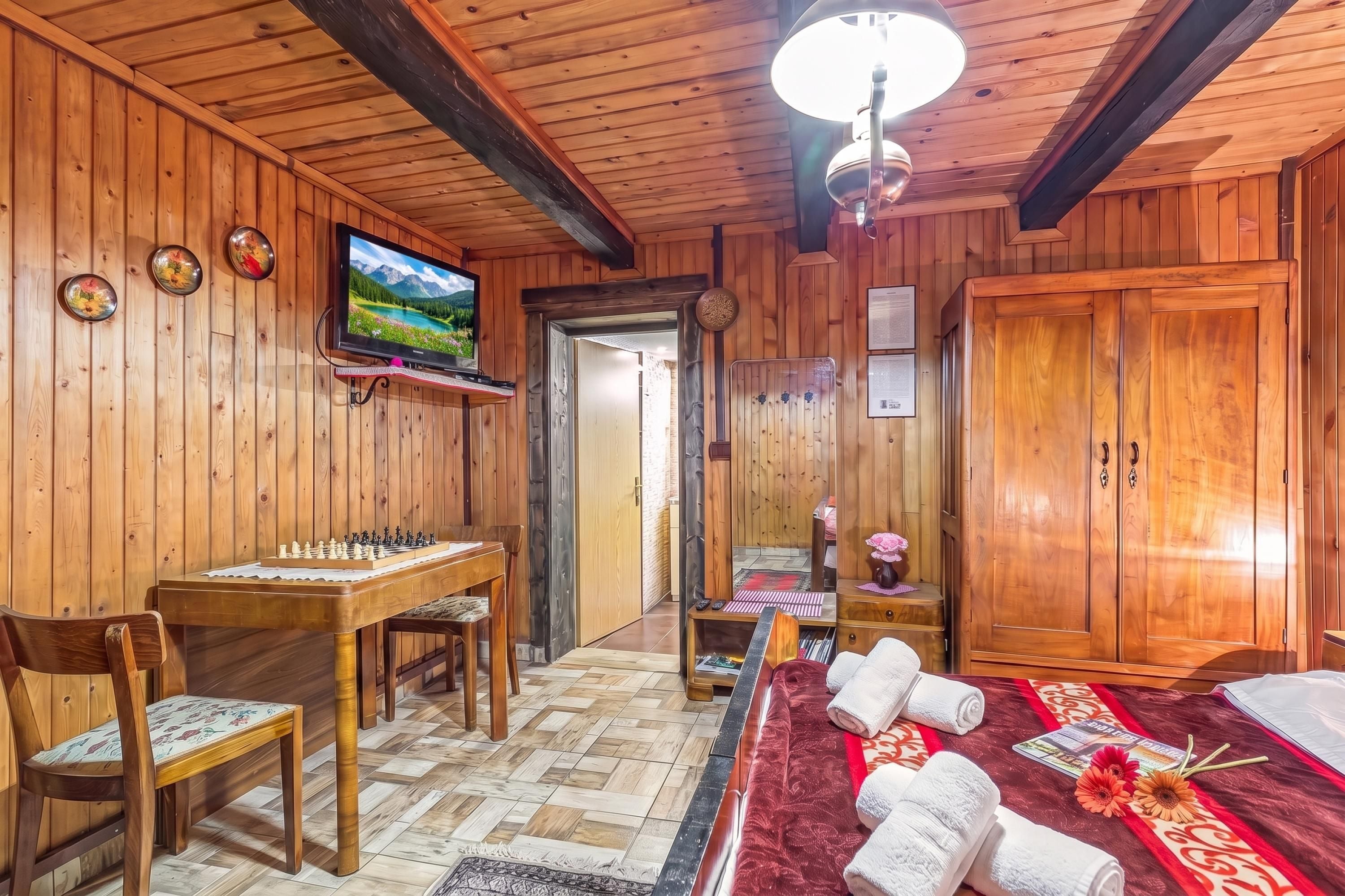 A wooden interior with a chessboard, a television, and a large mirror.
