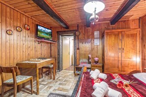 Un intérieur en bois avec un jeu d’échecs, un téléviseur et un grand miroir.