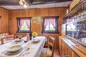 A wooden interior with a dining table set for two, a bottle of wine, and a bowl of fruit. - Chalet Birchwood With Hot Tub and Sauna (Breznički Hum)