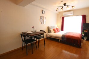 A compact room with a bed, a dining table with chairs, a clock, and an air conditioner. - 406 Equipped with fixed WiFi Near Hakata station - Pine Hills Minoshima 406 / Fukuoka Fukuoka (Fukuoka)