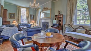 A traditional room with a fireplace, leather furniture, and a chandelier. - Historic Warrenton Home w/ Patio & Hot Tub! (Warrenton)