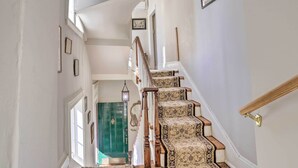 A staircase with patterned carpet and wooden railings leading to a door. - Historic Warrenton Home w/ Patio & Hot Tub! (Warrenton)