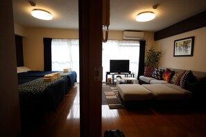 A hotel room with a bed, a sofa, a TV, and a small table.