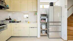 A compact kitchen with light-colored cabinets, a microwave, a toaster, and a refrigerator. - Private lodging in WEST TOKYO(SHINJUKU, TACHIKAWA, SANRIO, GHIBLI, MT. TAKAOetc) (Kokubunji)