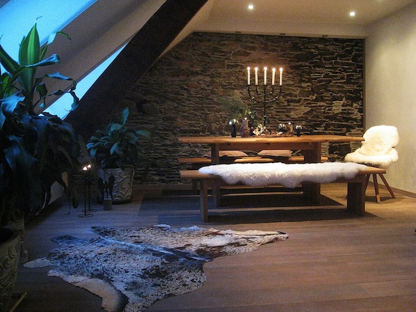 Ein moderner Essbereich mit Steinwand, Holztisch und weißem Fellstuhl.