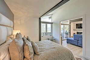 Ein Schlafzimmer mit einem großen Bett, einem Nachttisch, einer Lampe und Blick auf den Balkon.