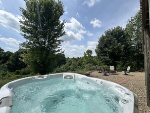 A hot tub with a view of a wooded area and a wooden deck with chairs. - Luxury Lodge on 125 acres on Hocking Hills Farm (Logan)