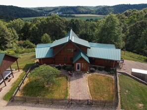 A large wooden lodge with a green roof, surrounded by a well-maintained lawn and a gravel driveway. - Luxury Lodge on 125 acres on Hocking Hills Farm (Logan)