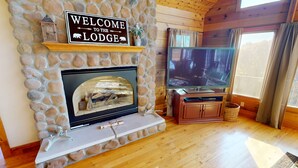 Una chimenea de piedra con un televisor y un letrero arriba que dice "WELCOME TO THE LODGE".