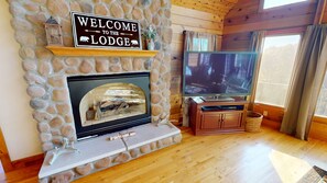 Una llar de pedra amb televisió i un cartell que diu "WELCOME TO THE LODGE".