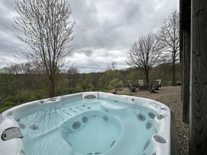 A hot tub with a view of a forest and outdoor seating area. - Luxury Lodge on 125 acres on Hocking Hills Farm (Logan)