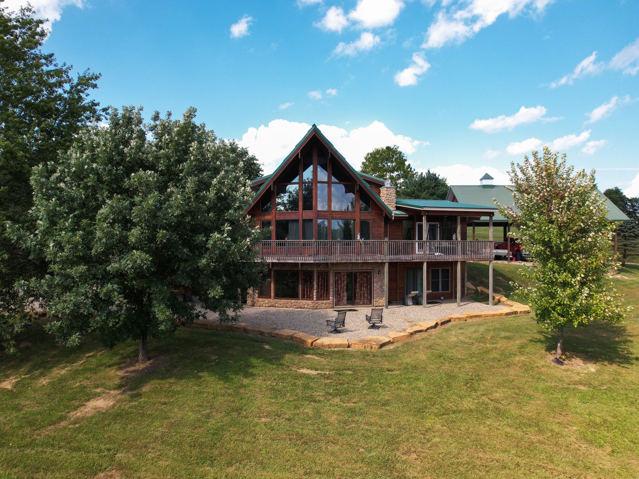 A large, two-story log cabin with a balcony and a covered porch.