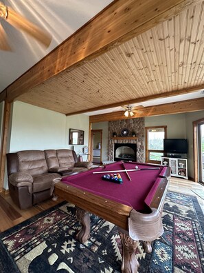 A pool table with a red felt surface, a brown leather sofa, and a patterned rug. - Luxury Lodge on 125 acres on Hocking Hills Farm (Logan)