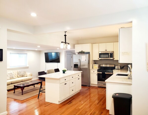 A modern kitchen with white cabinets, stainless steel appliances, and a central island.